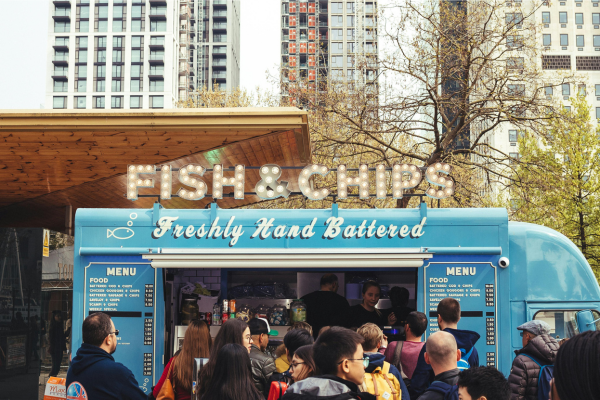 a well equipped food truck with customers all around it trying to buy different items